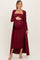 woman wearing a burgundy maternity ribbed dress with a long cardigan and holding her baby bump