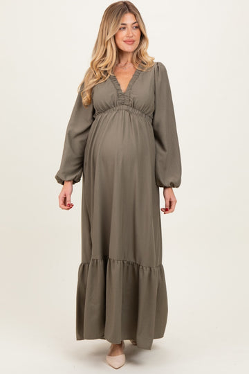 woman wearing a sage green long sleeve maternity dress with a v-neckline and tiered skirt, showcasing her baby bump