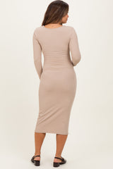 woman wearing a light tan long sleeve ribbed maternity dress, view from the back, fitted style