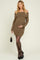woman wearing a brown off-shoulder knitted maternity dress and holding her baby bump