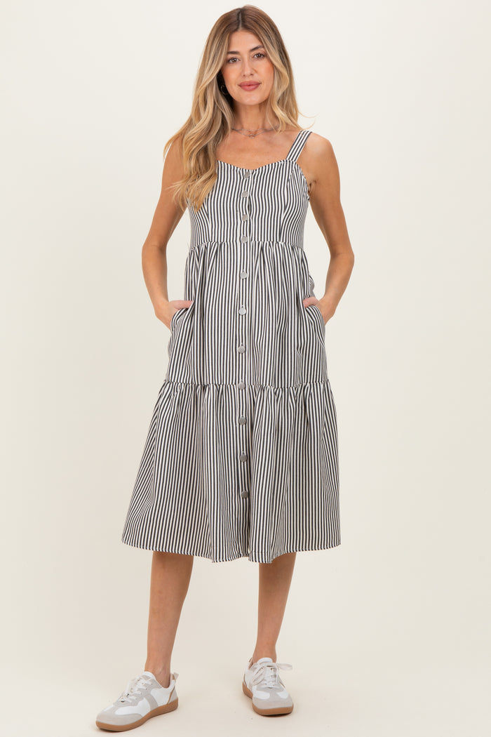 woman wearing a striped maternity sundress with pockets and buttons, standing in casual sneakers