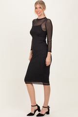 woman wearing a black polka dot mesh midi dress with long sleeves and a fitted silhouette