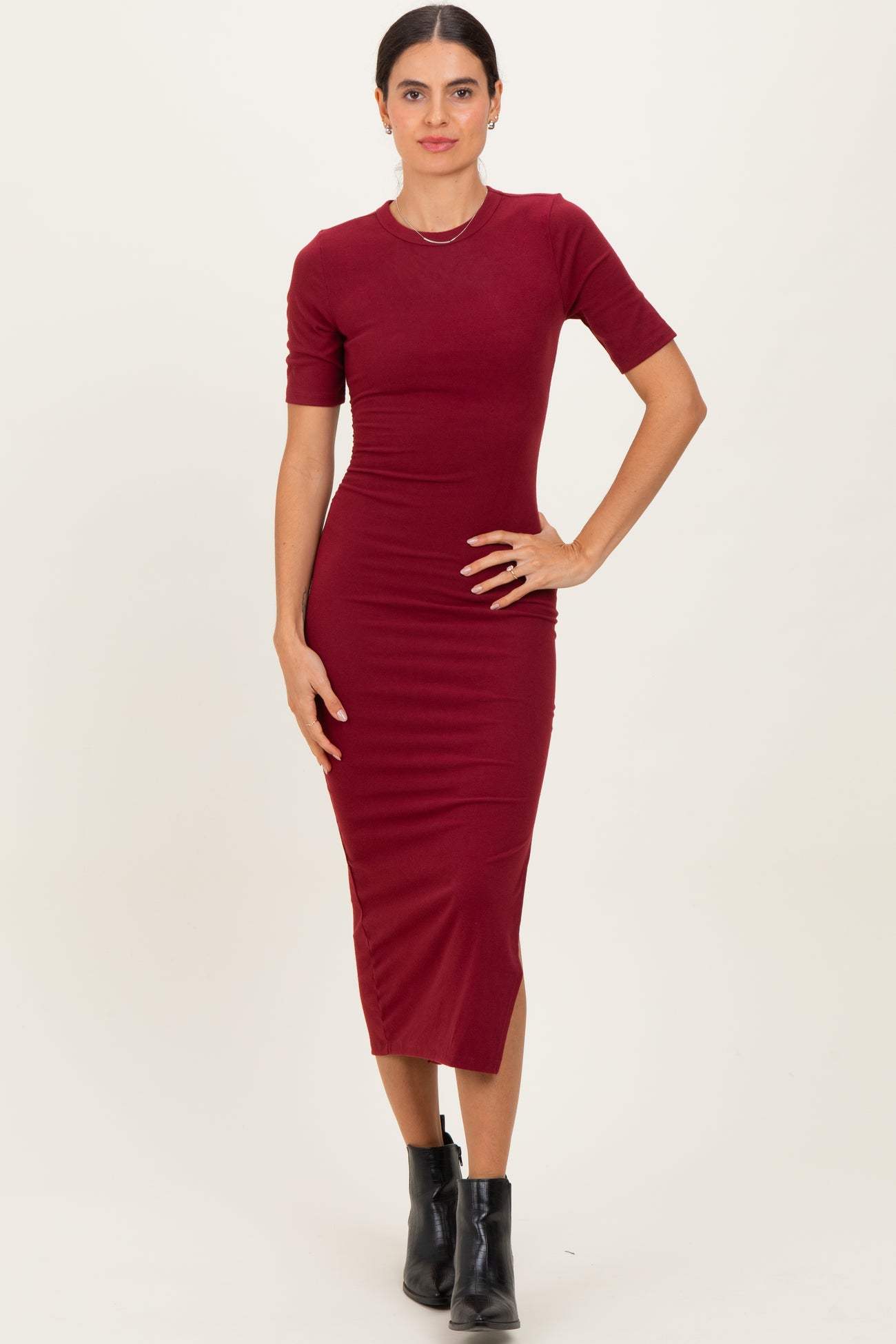 woman wearing a fitted burgundy midi dress with short sleeves and a round neckline, standing confidently