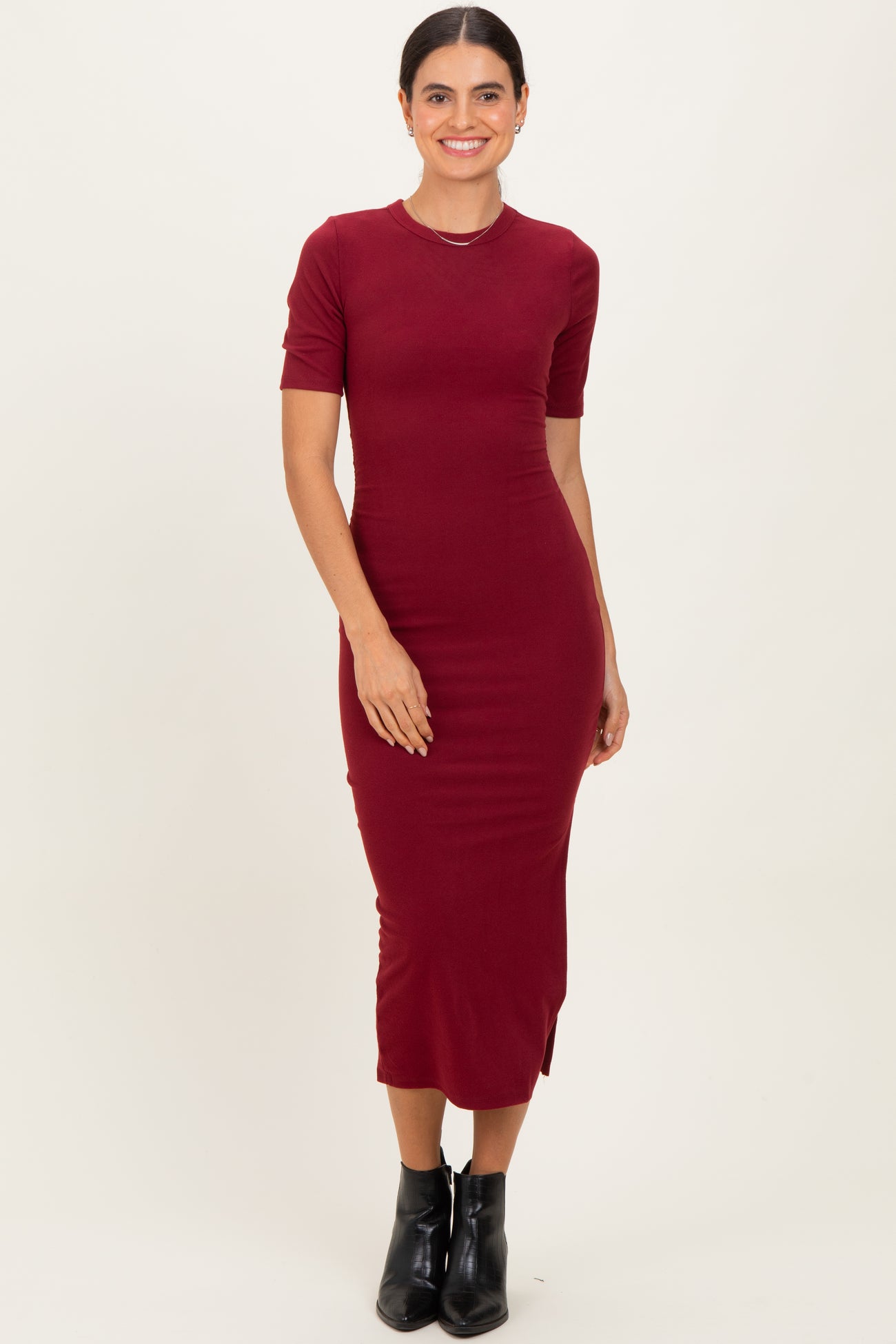 woman wearing a burgundy short sleeve midi dress with side slits and a fitted silhouette