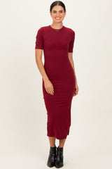 woman wearing a burgundy short sleeve midi dress with side slits and a fitted silhouette