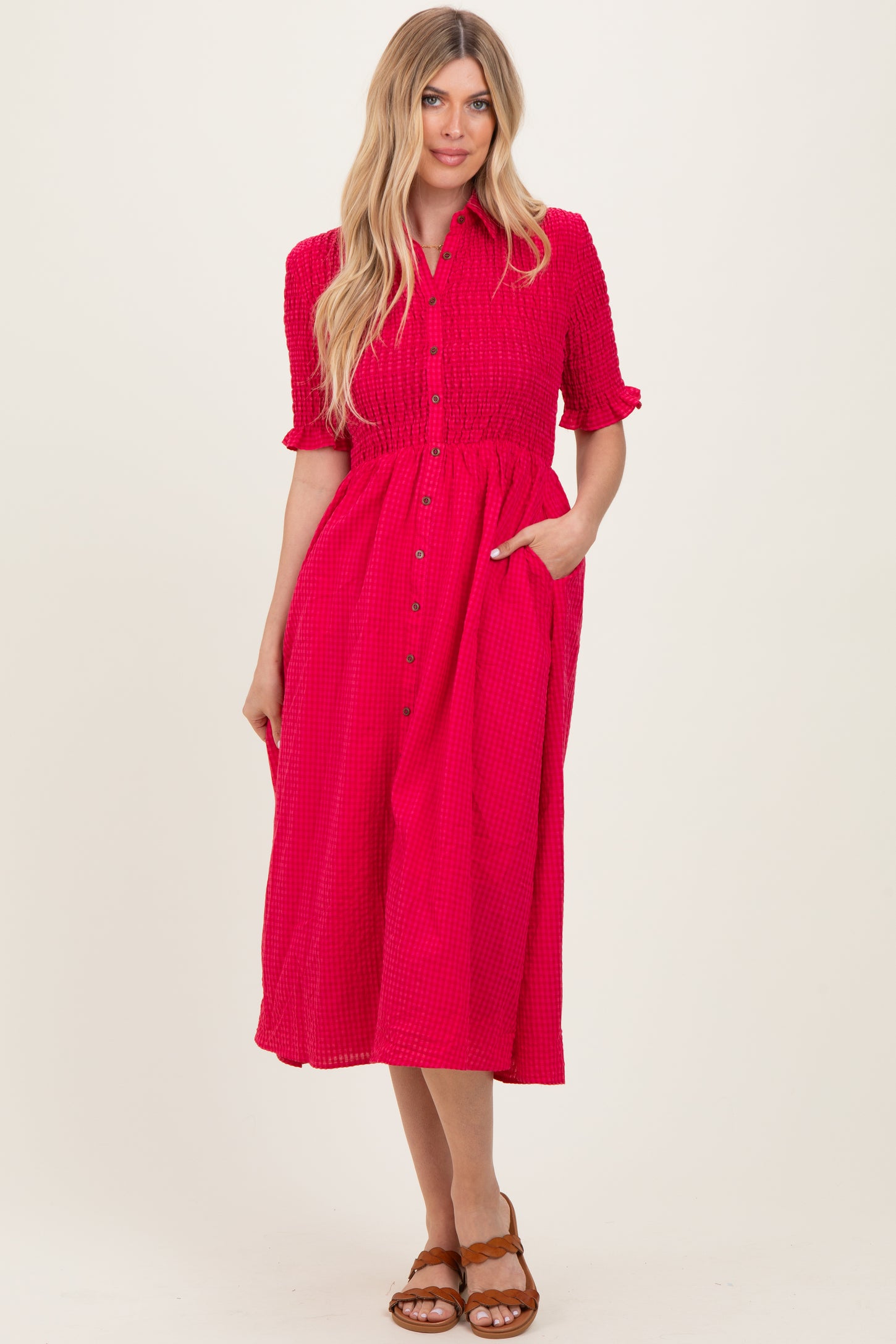woman wearing a bright pink button-up midi dress with short sleeves and pockets