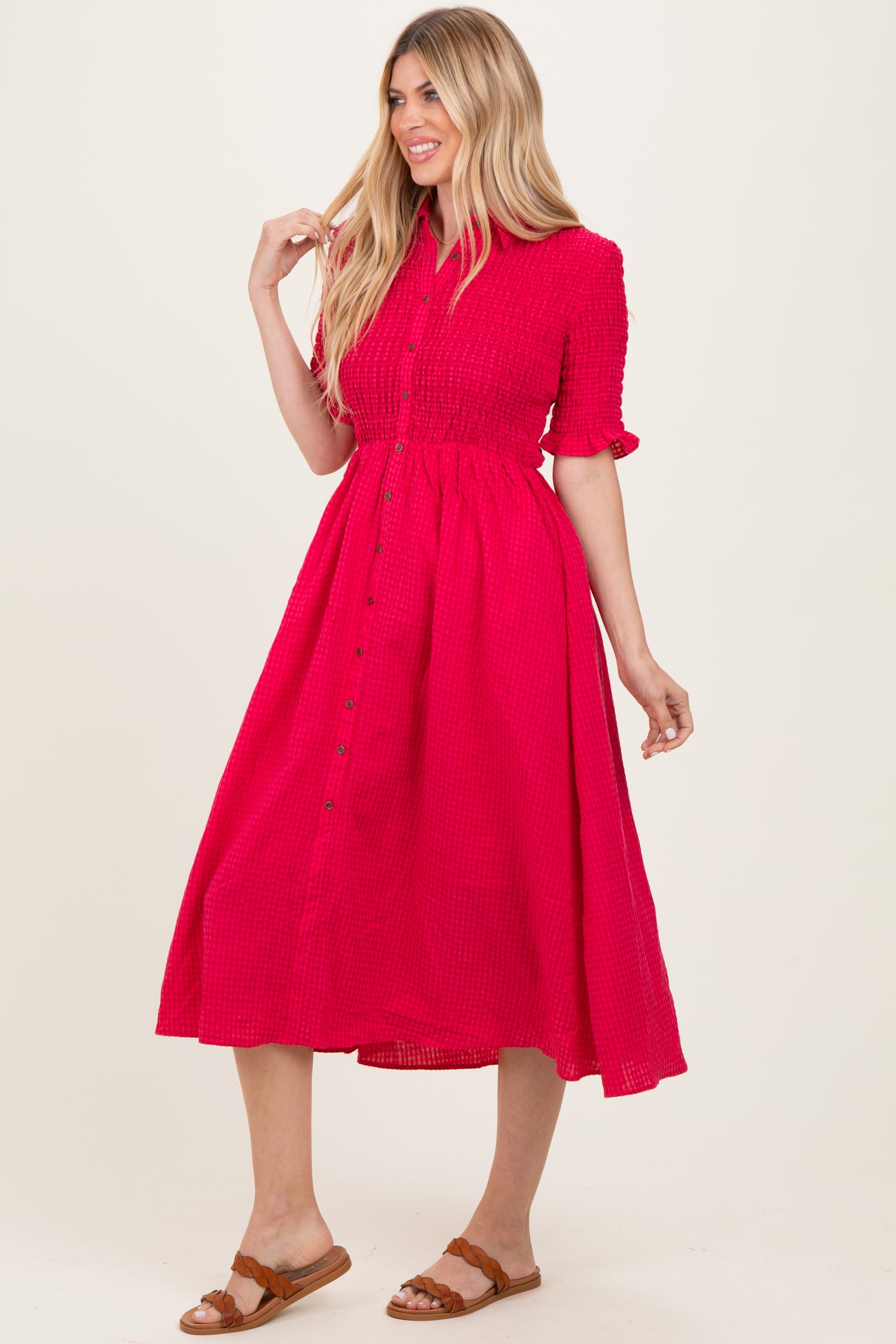 woman wearing a bright pink button-up midi dress with short sleeves and a cinched waist