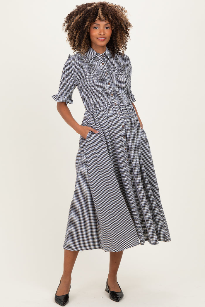 woman wearing a black and white gingham maternity dress with a smocked waist and pockets, displaying a baby bump