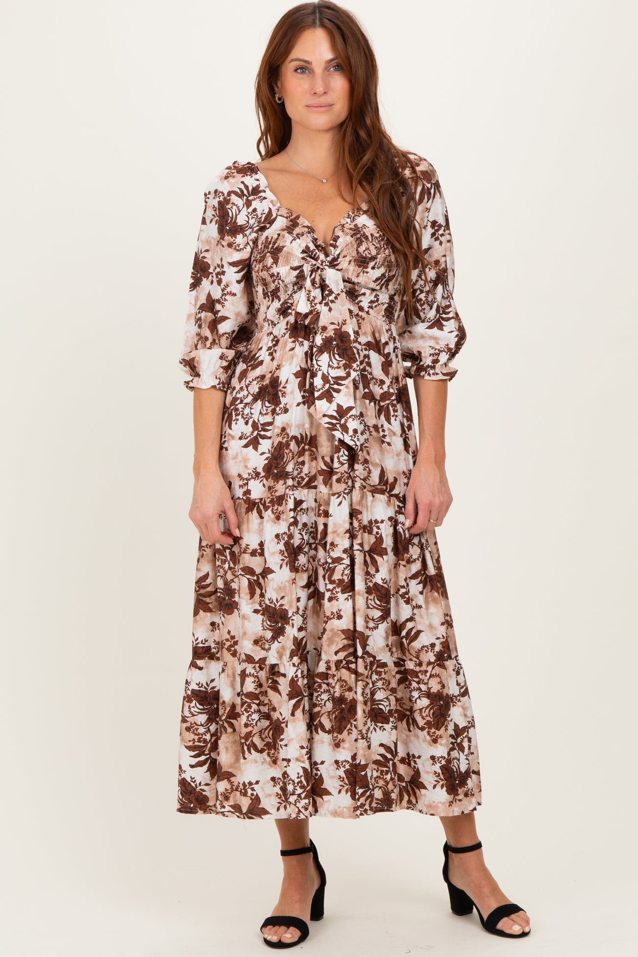 woman wearing a brown and cream floral maxi dress with puff sleeves and a tiered skirt