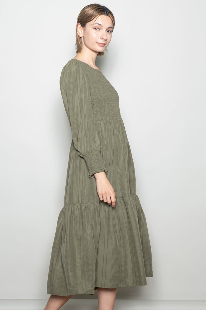 woman wearing an olive green long sleeve tiered midi dress with a smocked bodice and puff sleeves