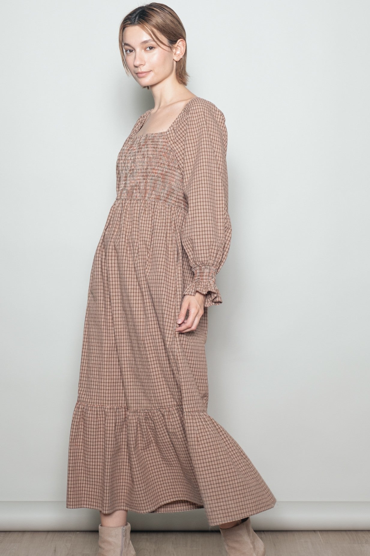 woman wearing a brown gingham long sleeve maxi dress with a smocked bodice and tiered hem