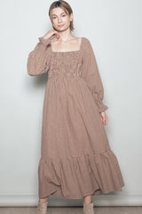 woman wearing a brown checkered long sleeve maxi dress with a square neckline and ruffled hem