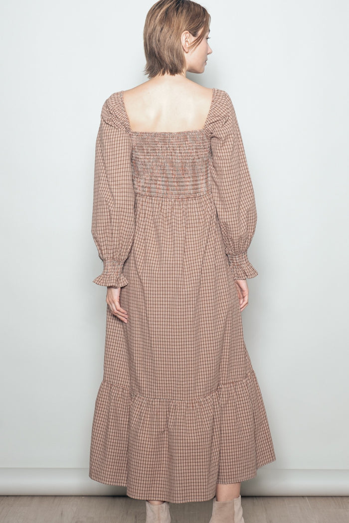 woman wearing a brown checkered long sleeve maxi dress with a smocked back and ruffled hem