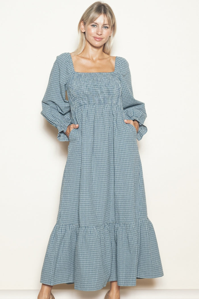 woman wearing a blue and white checkered long sleeve maxi dress with a square neckline and pockets
