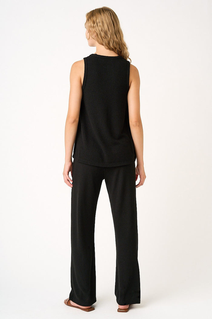 woman wearing a black sleeveless top and matching loose-fitting pants, seen from the back