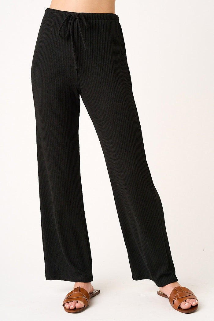 woman wearing black ribbed wide-leg pants with an elastic waistband and drawstring, paired with brown sandals
