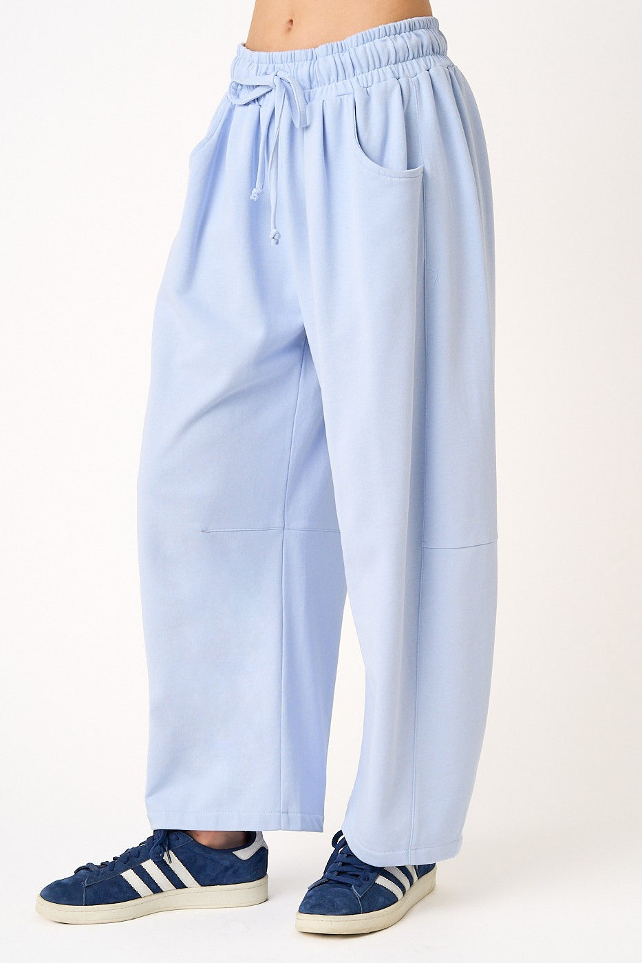 woman wearing light blue wide-leg pants with an elastic waistband and side pockets, paired with blue sneakers