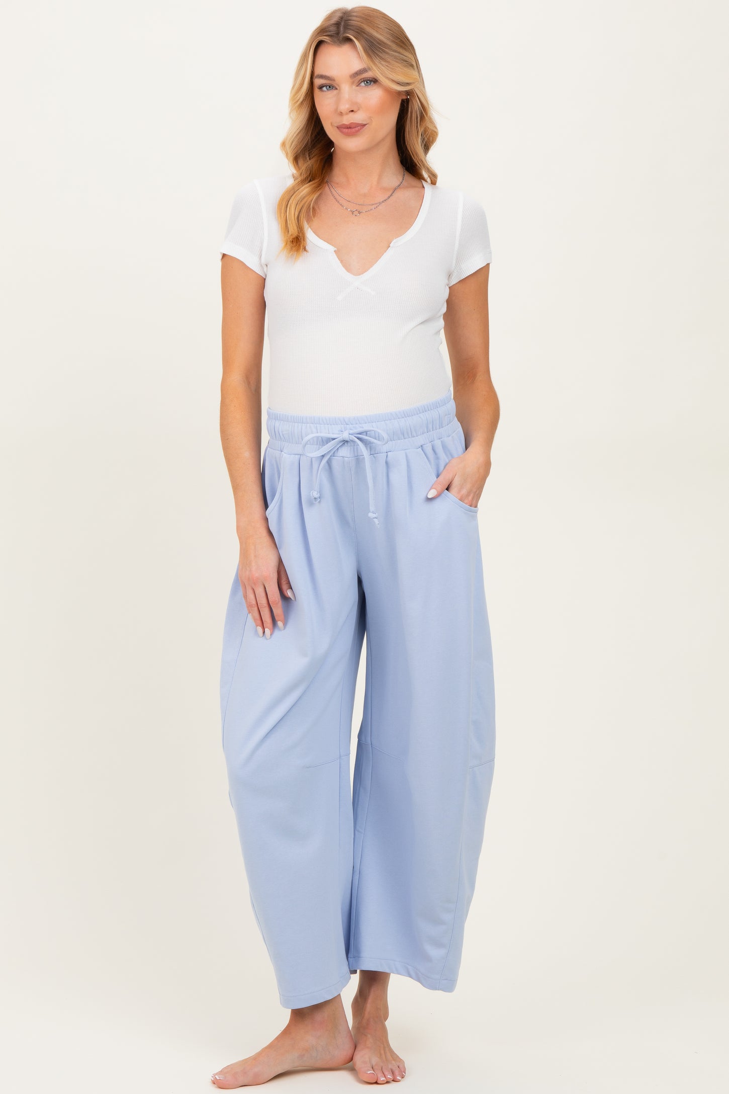 woman wearing a white short sleeve ribbed maternity top and light blue maternity wide leg pants with pockets