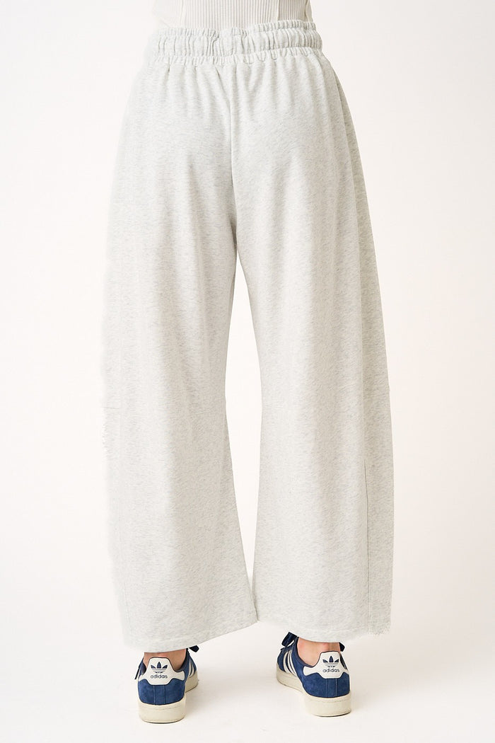 woman wearing gray wide-leg sweatpants with an elastic waistband and casual sneakers