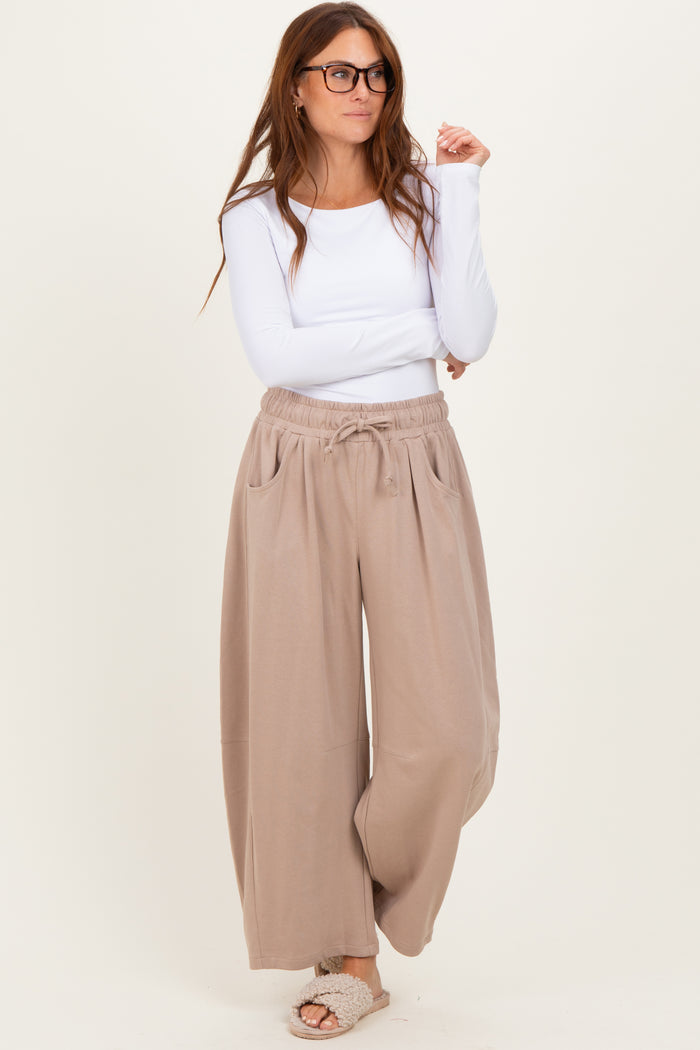 woman wearing a white long sleeve top and taupe wide-leg pants with drawstring waist