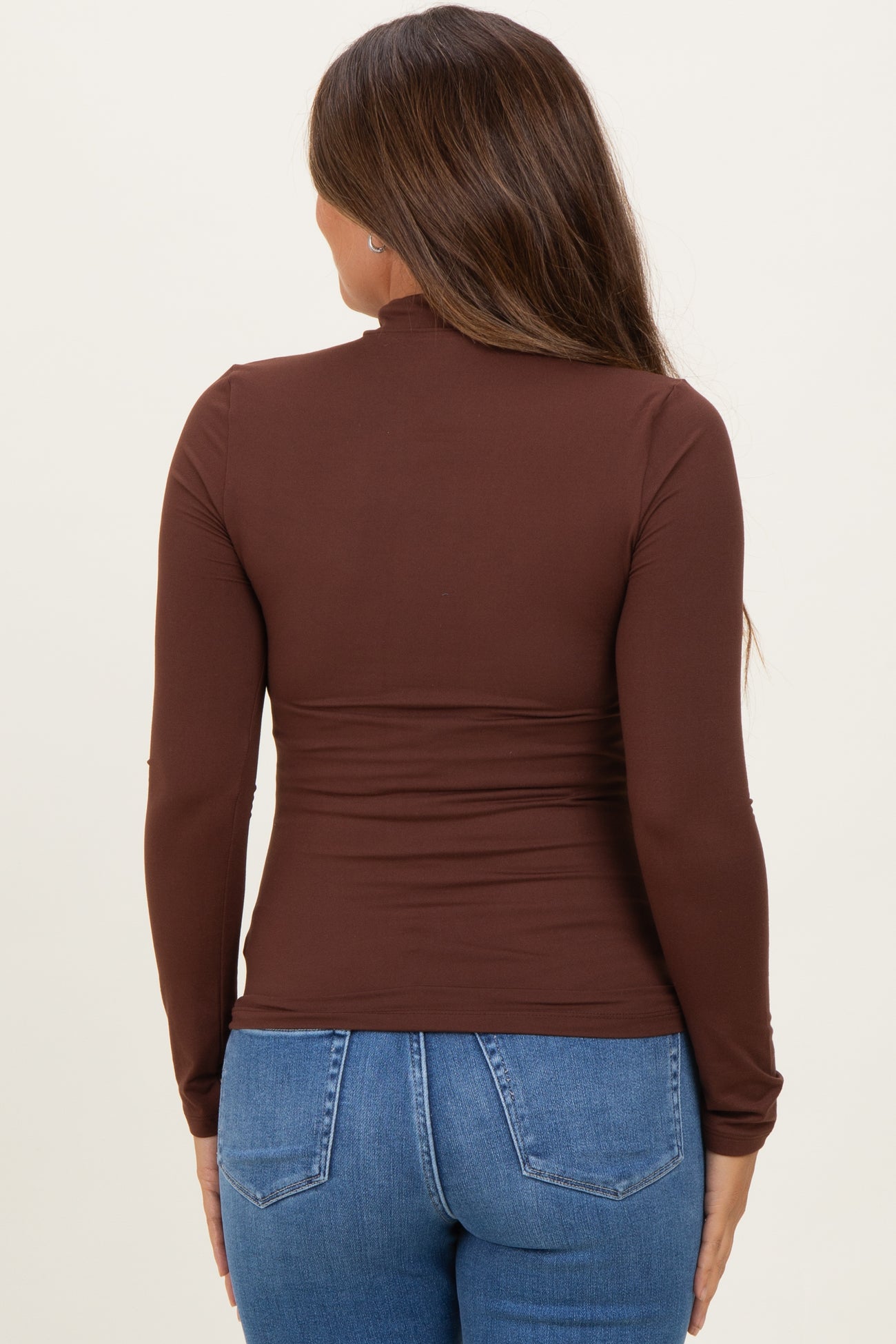 woman wearing a brown long sleeve maternity top with a fitted design, viewed from the back