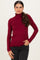 woman wearing a burgundy long sleeve turtleneck top with a fitted silhouette and side gathering, paired with black jeans