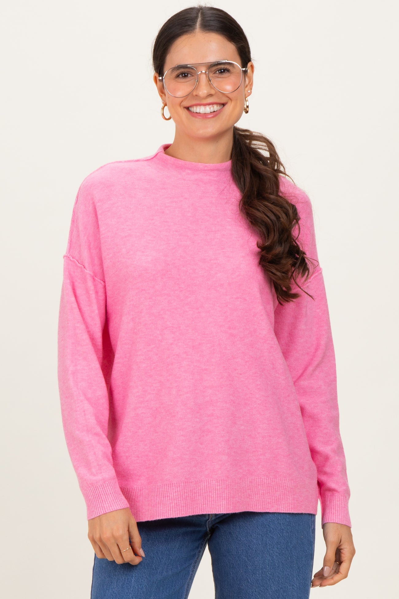 woman wearing a pink long sleeve oversized sweater with a high neckline and relaxed fit