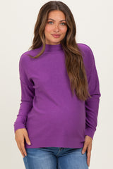 woman wearing a purple maternity sweater with a high neck and relaxed fit, showing her baby bump