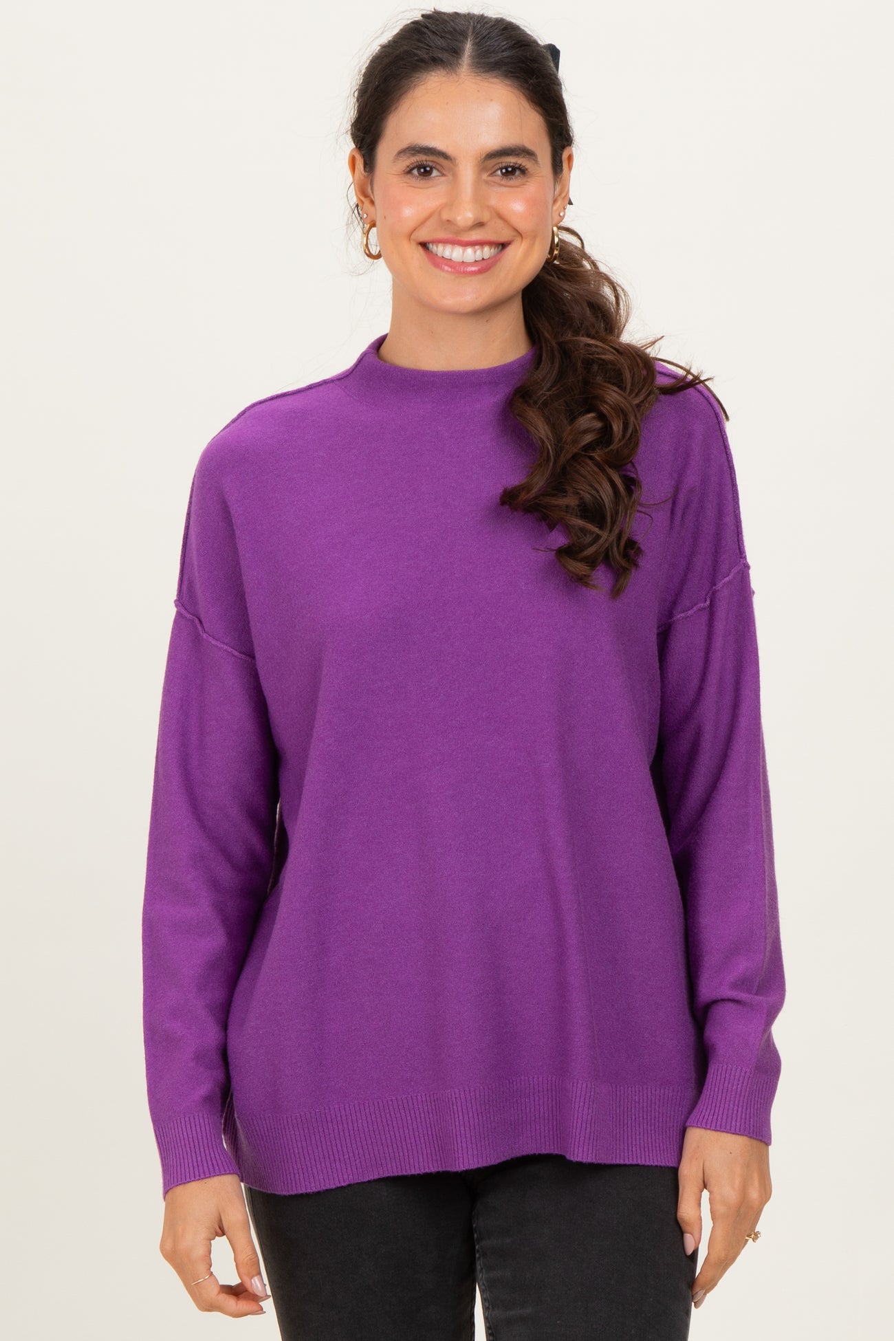 woman wearing a purple long sleeve sweater with a relaxed fit and ribbed hem