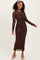 woman wearing a brown long sleeve ruched midi dress with floral lace details and styled with a headband