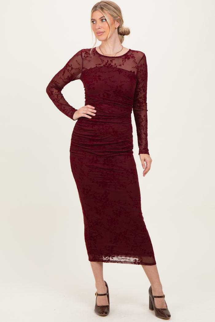 woman wearing a burgundy long sleeve bodycon dress with floral lace details and a fitted silhouette