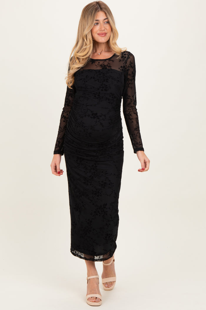 woman wearing a black long sleeve maternity dress with floral patterns and ruching on the sides, showing her baby bump