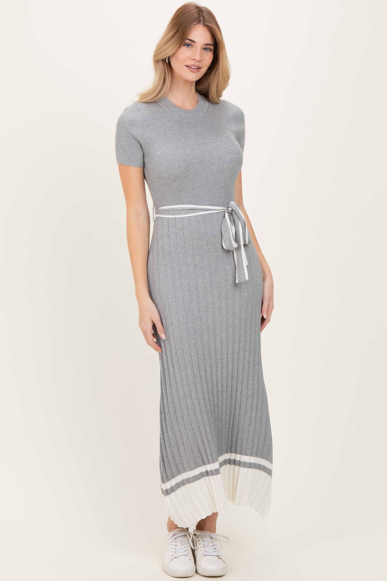 woman wearing a gray ribbed knit maxi dress with short sleeves, a tie belt, and white stripe details at the hem