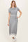woman wearing a gray ribbed maxi dress with short sleeves and a tied waist, styled with white accents at the hem