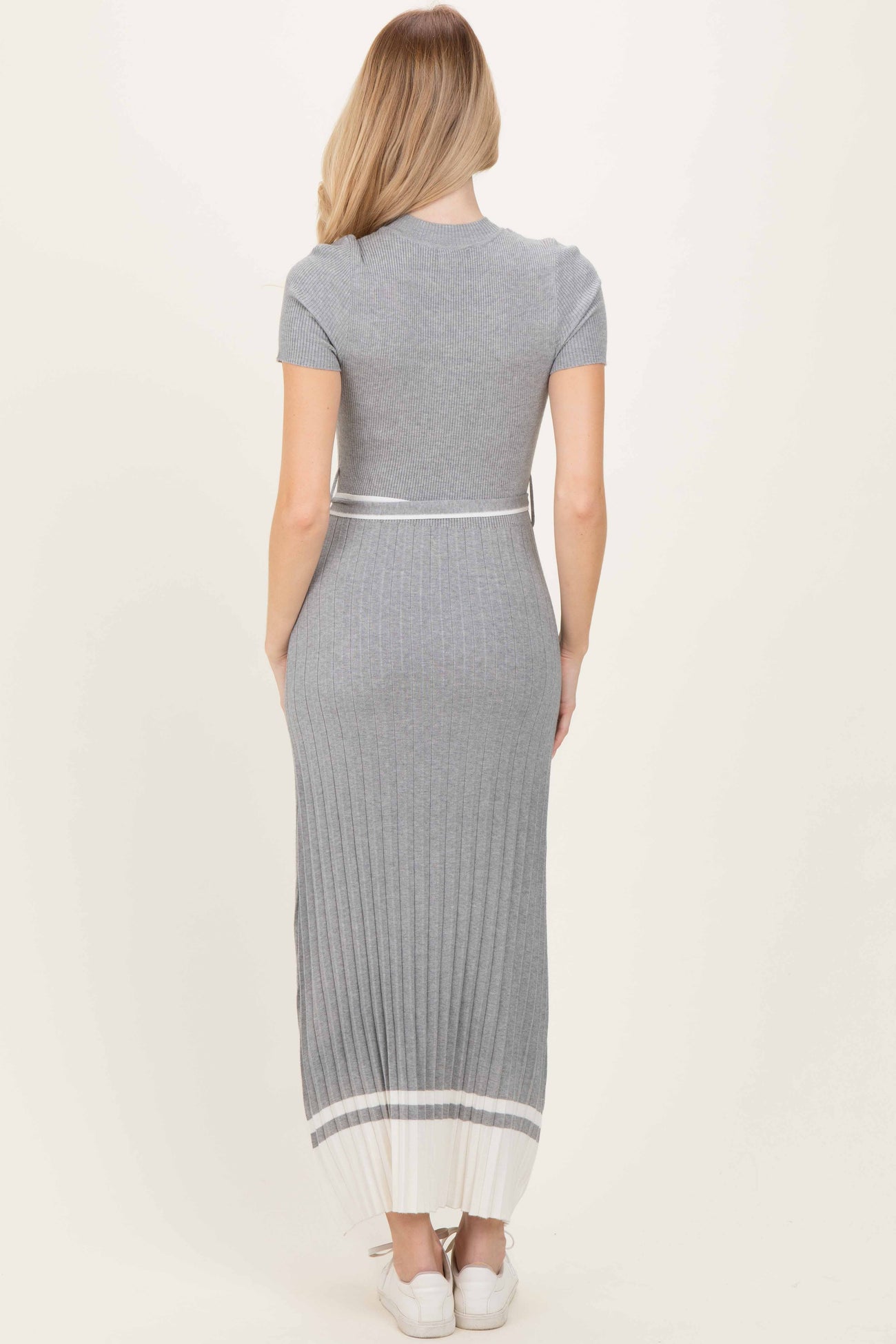 woman wearing a grey ribbed maxi dress with short sleeves and a white striped hem, viewed from the back