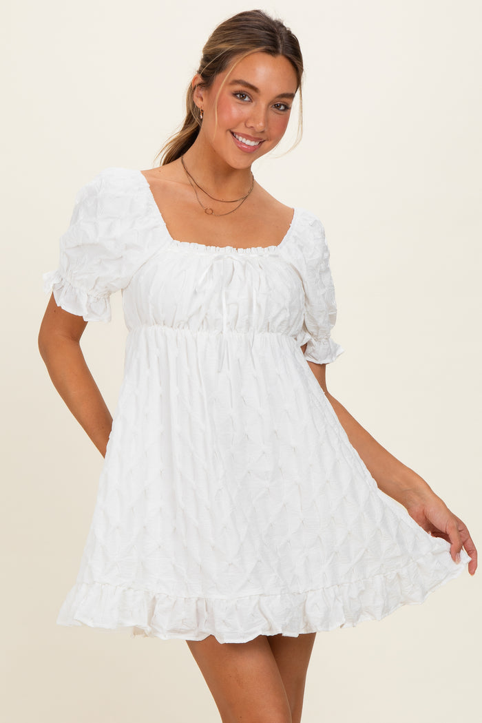 woman wearing a white puff sleeve mini dress with a square neckline and ruffle hem