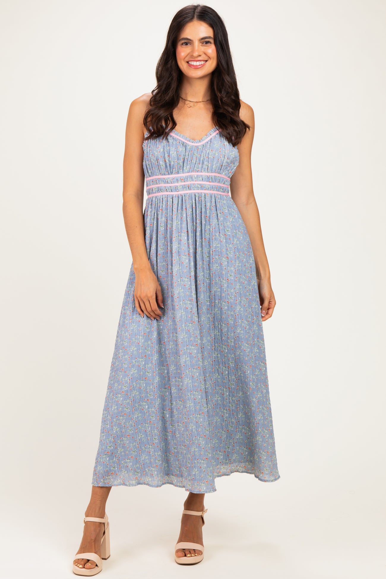 woman wearing a light blue floral maxi dress with a smocked bodice and braided detail, standing on a neutral background
