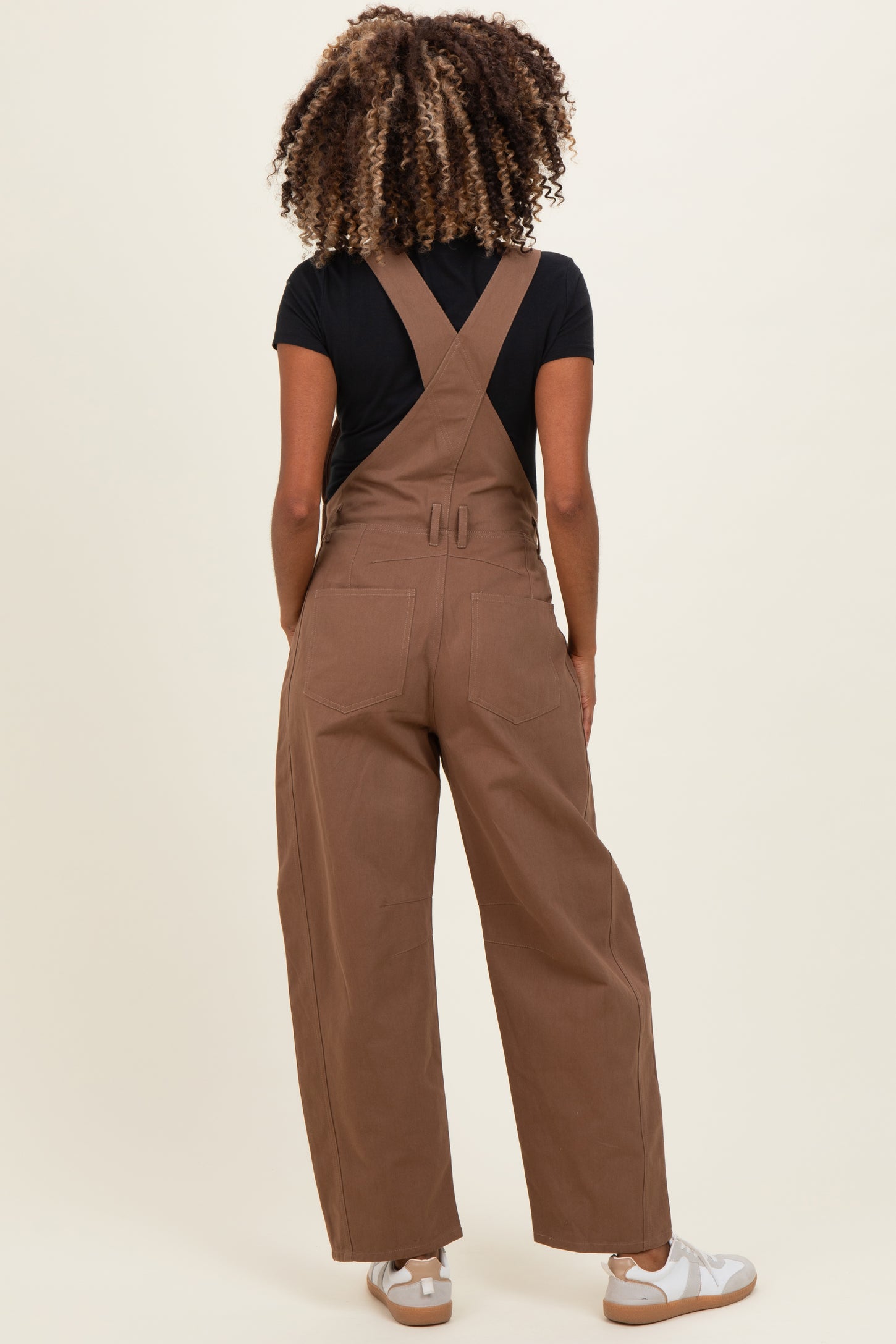 woman wearing brown maternity overalls with a fitted top, shown from the back
