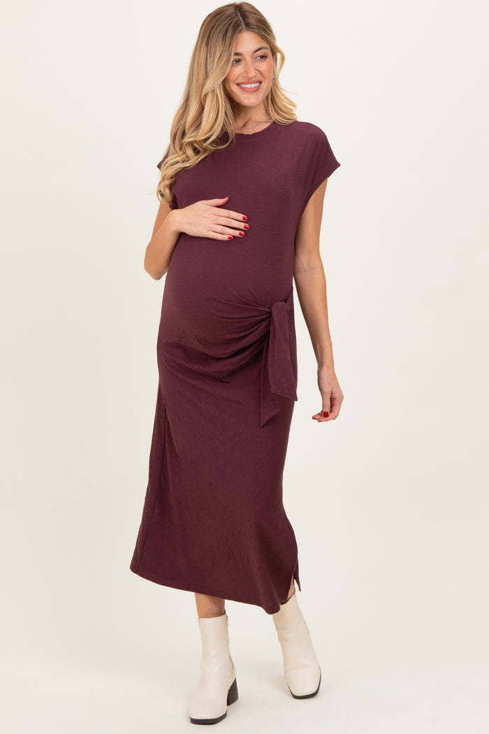 woman wearing a burgundy maternity dress with a side tie detail and showing her baby bump