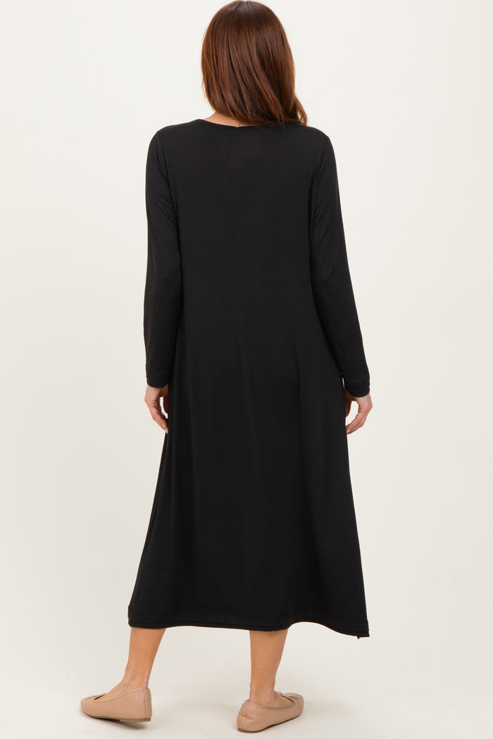 woman wearing a black long sleeve maxi dress, viewed from the back, with tan slip-on shoes