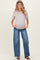 woman wearing a light gray short sleeve maternity top and distressed wide-leg jeans, showing her baby bump