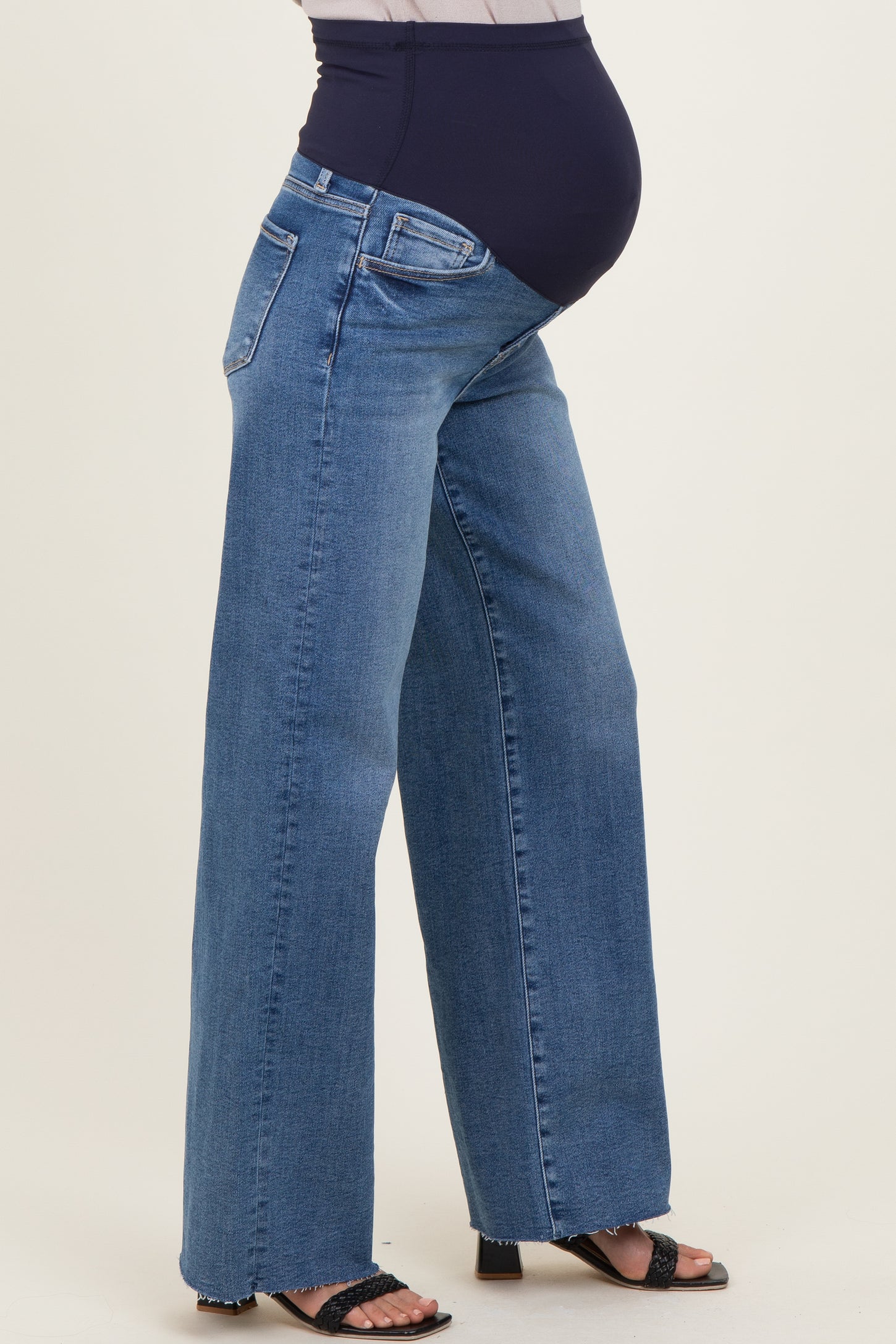 woman wearing a pair of wide-leg blue maternity jeans with a stretchy black waistband and a visible baby bump