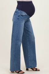 woman wearing a pair of wide-leg blue maternity jeans with a stretchy black waistband and a visible baby bump