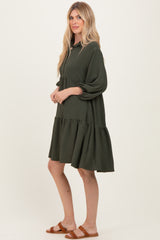 woman wearing a dark green tiered dress with puff sleeves and a collar, standing sideways