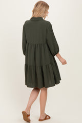 woman wearing an olive green tiered dress with three-quarter puff sleeves, seen from the back