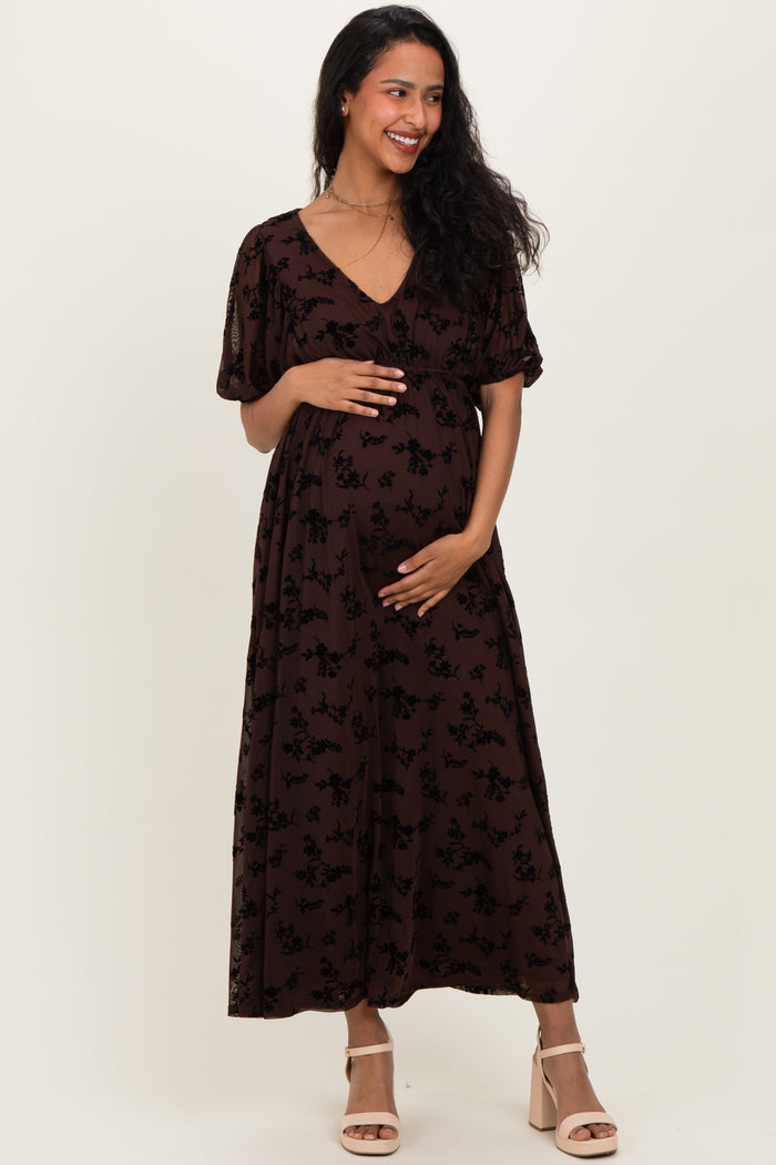 woman wearing a brown floral maternity maxi dress and holding her baby bump