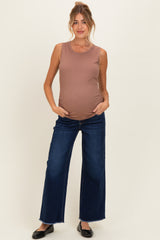 woman wearing a brown ribbed maternity tank top and dark blue wide-leg jeans, showcasing her baby bump