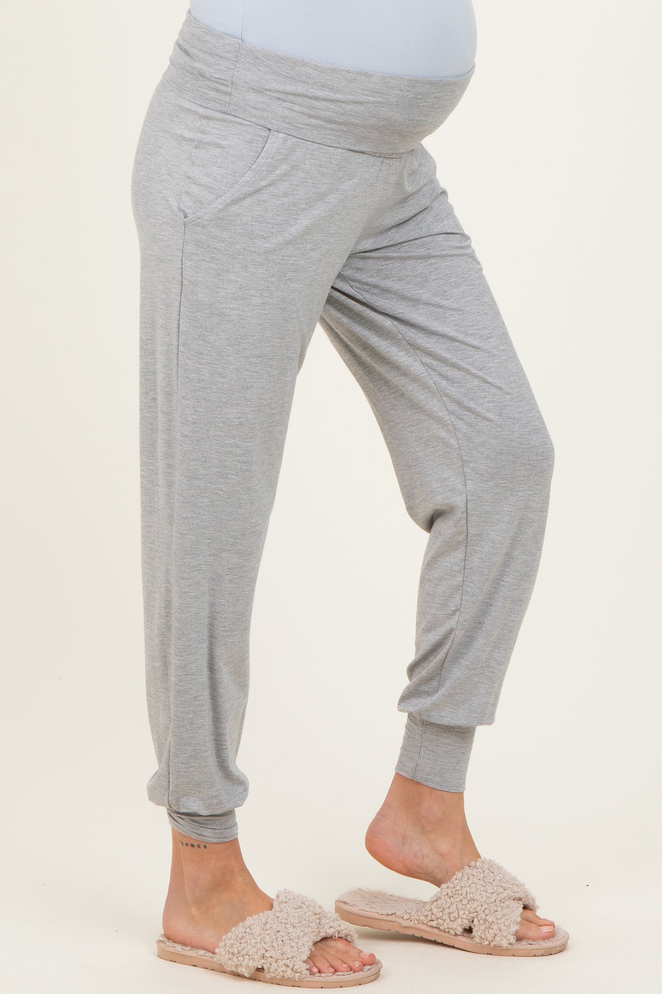 woman wearing gray maternity joggers with a wide waistband and pockets, showing her baby bump