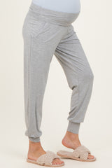 woman wearing gray maternity joggers with a wide waistband and pockets, showing her baby bump