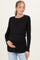 woman wearing a black ribbed maternity top with a cropped hem and holding her baby bump
